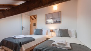 A hotel room with two beds, each with a pillow, a bedside table, and a lamp. There is a framed picture on the wall above the beds. - FLH Lisbon Sun Terrace Graça IV (Lisbon)