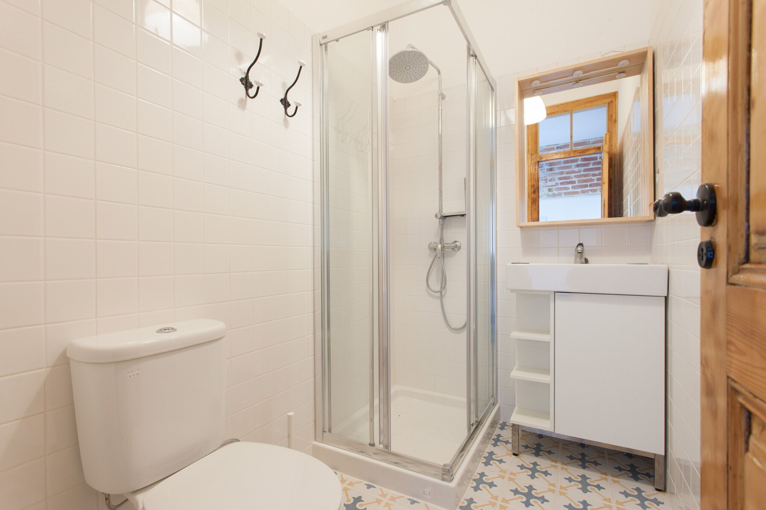 A bathroom with a toilet, a glass-enclosed shower, a sink, and a mirror.