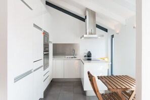 Une cuisine moderne avec des meubles blancs, un four encastré, un évier et une table en bois.