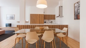 A modern kitchen with wooden accents, a glass dining table, and a pendant light. - FLH Baixa Spacious Apartment (Lisbon)