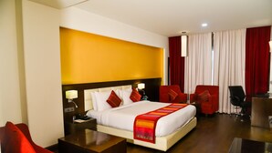 A hotel room with a bed, a desk, a chair, and a red couch. - Hotel Almeida (Dera Bassi)