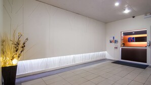 Ein Empfangsbereich mit Empfangstresen, einer Wandtafel und einer Zimmerpflanze.
