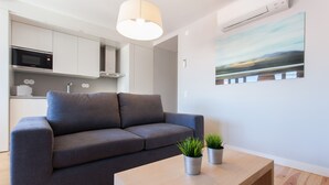 A modern living room with a grey sofa, a wooden coffee table, and two potted plants. - FLH Príncipe Real Luxus Apartment II (Lisbon)
