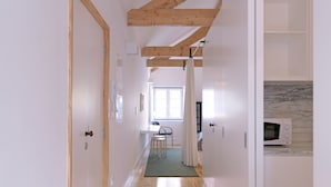 A hallway with wooden floors and exposed beams, leading to a dining area with a table and chairs. - FLH Porto Modern Rooftop (Oporto)