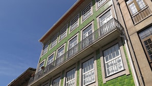 A multi-story building with green brick facade, multiple windows, and balconies. - FLH Porto Modern Rooftop (Oporto)