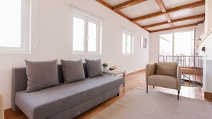 Un salon moderne avec un canapé gris, un fauteuil beige et une petite table d’appoint agrémentée d’une plante.