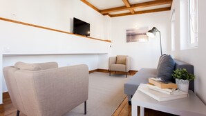 Un salon moderne avec un canapé, un fauteuil et une table basse agrémentée de livres et d’une plante.