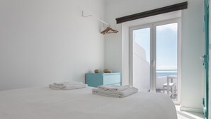Une chambre à coucher avec un lit, une armoire bleue et un balcon offrant une vue.