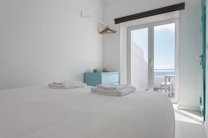 A bedroom with a bed, a blue cabinet, and a balcony with a view.