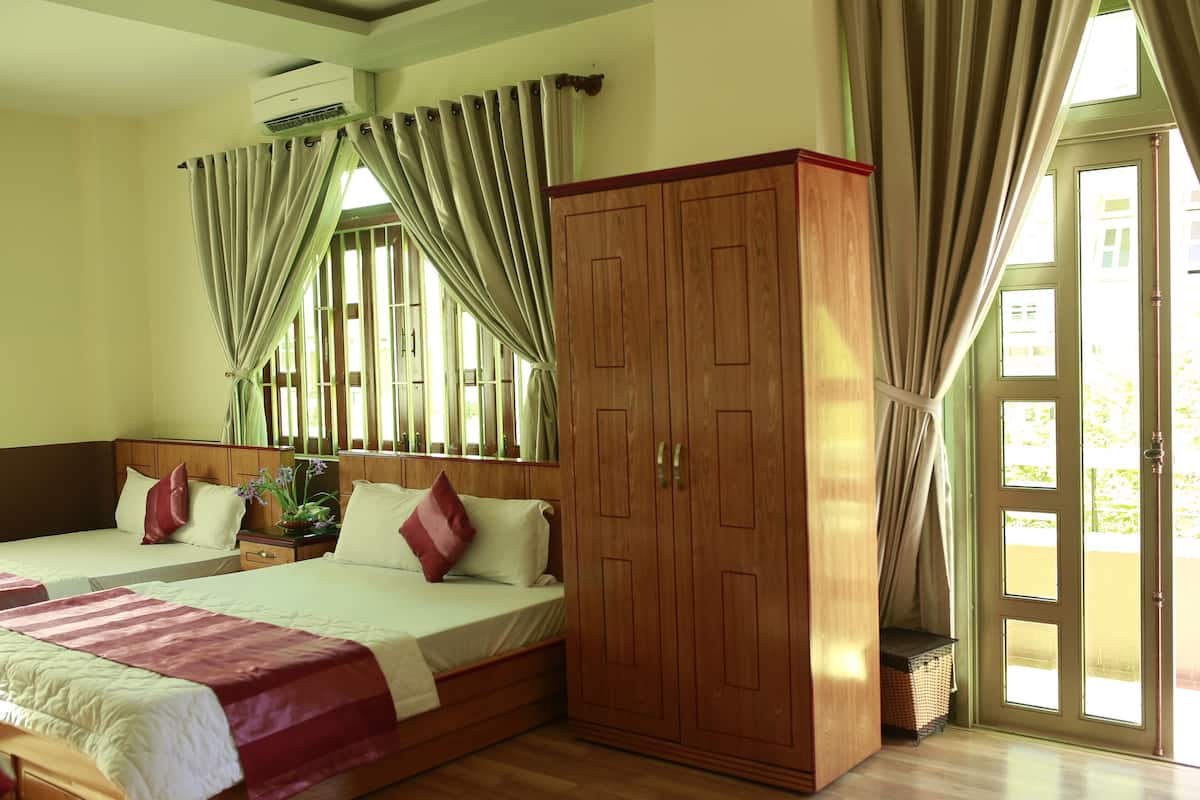 Une chambre d’hôtel avec deux lits, une armoire et une grande fenêtre avec des rideaux.