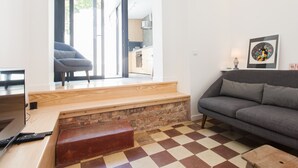 Un saló modern amb un terra de pissos, un sofà gris, una banca de fusta i un ordinador portàtil sobre una taula de fusta.