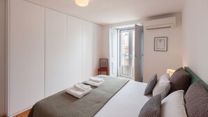 A hotel room with a bed, a wardrobe, a chair, and a window with a view.