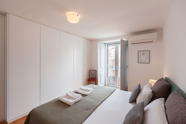 A hotel room with a bed, a wardrobe, a chair, and a window with a view.