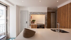 A modern kitchen with a central island, stainless steel sink, and wooden paneling.