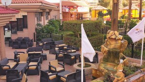 An outdoor seating area with wicker furniture and a stone fountain. - Jewel Al Nasr Hotel & Apartments (Cairo)