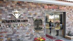 A restaurant with a stone facade, a signboard with text, and a flower bed in front. - Jewel Al Nasr Hotel & Apartments (Cairo)
