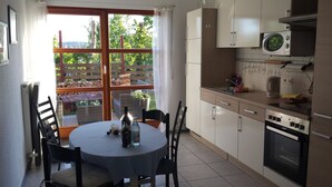 A kitchen with a dining table, chairs, a microwave, and an oven. - Apartment "lake Ehmetsklinge" (Zaberfeld)