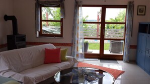 A living room with a sofa, a glass coffee table, a fireplace, and a view of the outdoors through large windows. - Apartment "lake Ehmetsklinge" (Zaberfeld)