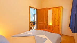 Ein Schlafzimmer mit einem Bett, einem Holzschrank und einem Schreibtisch mit Stuhl.