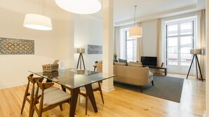 Un salón amplio con una mesa de vidrio, sillas de madera, un sofá y una televisión.