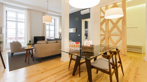 Una sala de estar moderna con una mesa de comedor de cristal, sofás y una televisión.
