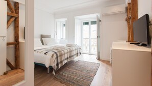 A bedroom with a bed, a television, and a view of the outside. - FLH Santa Marta Portuguese Flat (Lisbon)