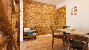 A dining area with a stone wall, wooden furniture, and a modern table. - FLH Santa Marta Portuguese Flat (Lisbon)