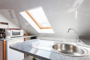A kitchen with a skylight, stainless steel sink, and modern appliances.