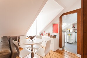 A modern loft apartment with a dining area, a kitchen, and a living room.