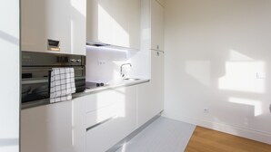 A modern kitchen with white cabinetry, a stainless steel oven, and a built-in microwave. - FLH Baixa Modern Place (Lisbon)