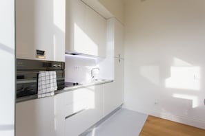 A modern kitchen with white cabinetry, a stainless steel oven, and a built-in microwave.