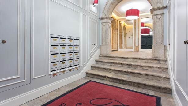 A hallway with a red carpet, a set of lockers, and a staircase leading to a room with a red light fixture. - FLH Baixa Modern Place (Lisbon)