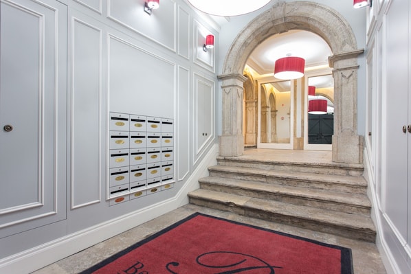 A hallway with a red carpet, a set of lockers, and a staircase leading to a room with a red light fixture.
