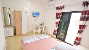 A bedroom with a bed, a desk, a chair, a wardrobe, a television, and a window with curtains. - Apartment for 2 guests with sea view in Herceg Novi (Meljine)