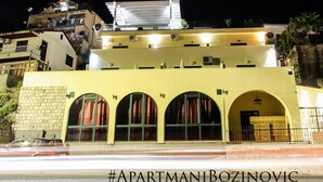 A building with a yellow facade, multiple balconies, and a large billboard on the roof. - Apartment for 2 guests with sea view in Herceg Novi (Meljine)