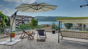 A terrace with a view of the sea, a table with a bottle and fruit, and a chair. - Apartment for 2 guests with sea view in Herceg Novi (Meljine)