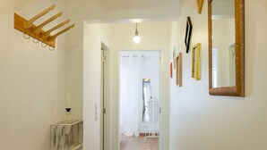 A hallway with a wooden coat rack, a mirror, and a door leading to another room. - FLH Marquês Bright Apartment (Lisbon)