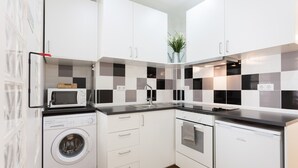 A compact kitchen with white cabinets, a microwave, a washing machine, and a dishwasher. - FLH Marquês Bright Apartment (Lisbon)