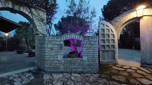 Une structure en pierre dotée d’une petite fenêtre et d’une porte, éclairée par un éclairage violet.