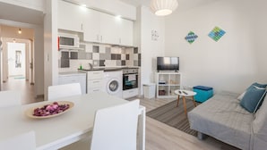 Un apartamento moderno con cocina, comedor y sala de estar. Incluye lavadora, microondas y televisor.