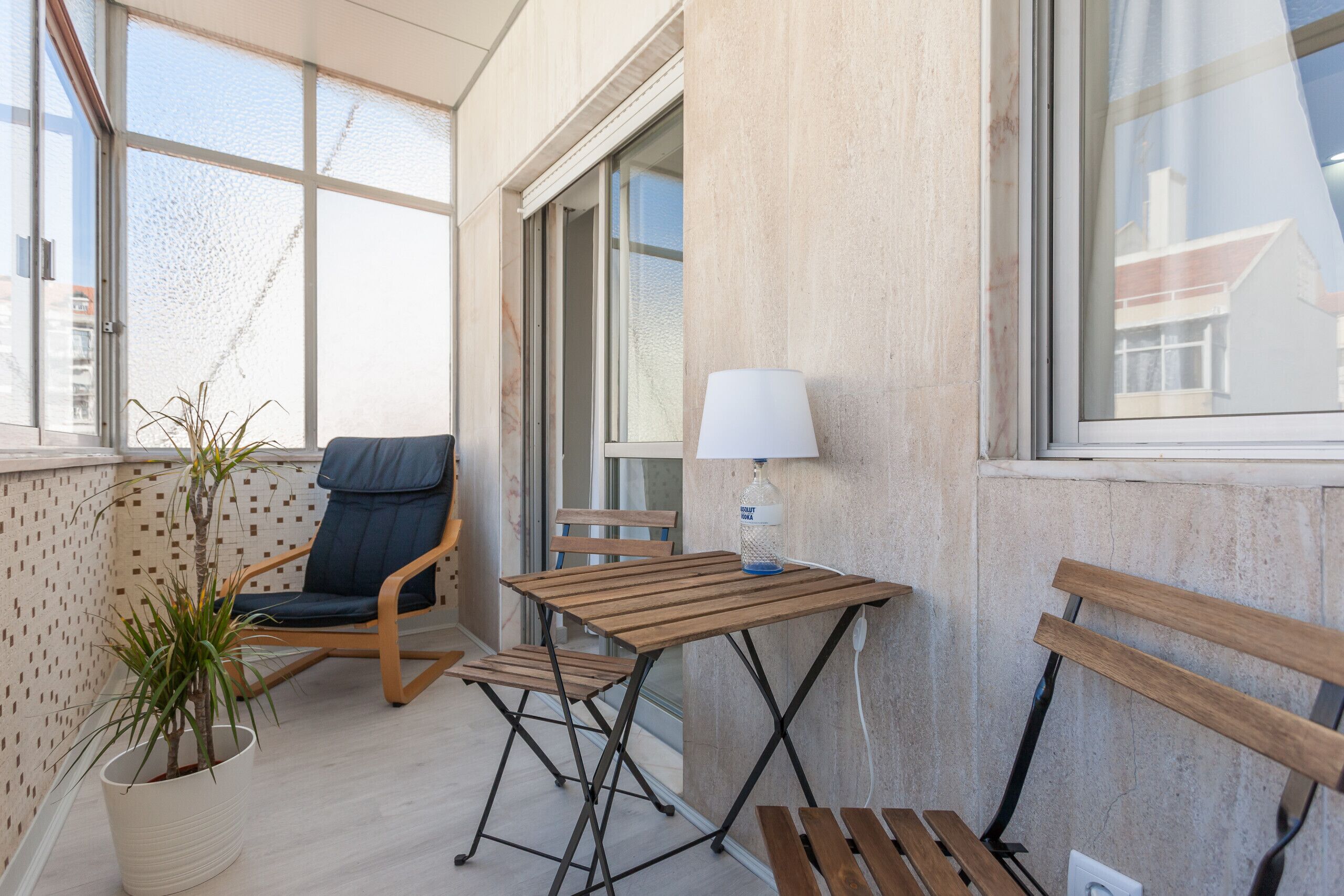 Ein Balkon mit Holztisch, Stühlen, einer Lampe und einem Blumentopf.