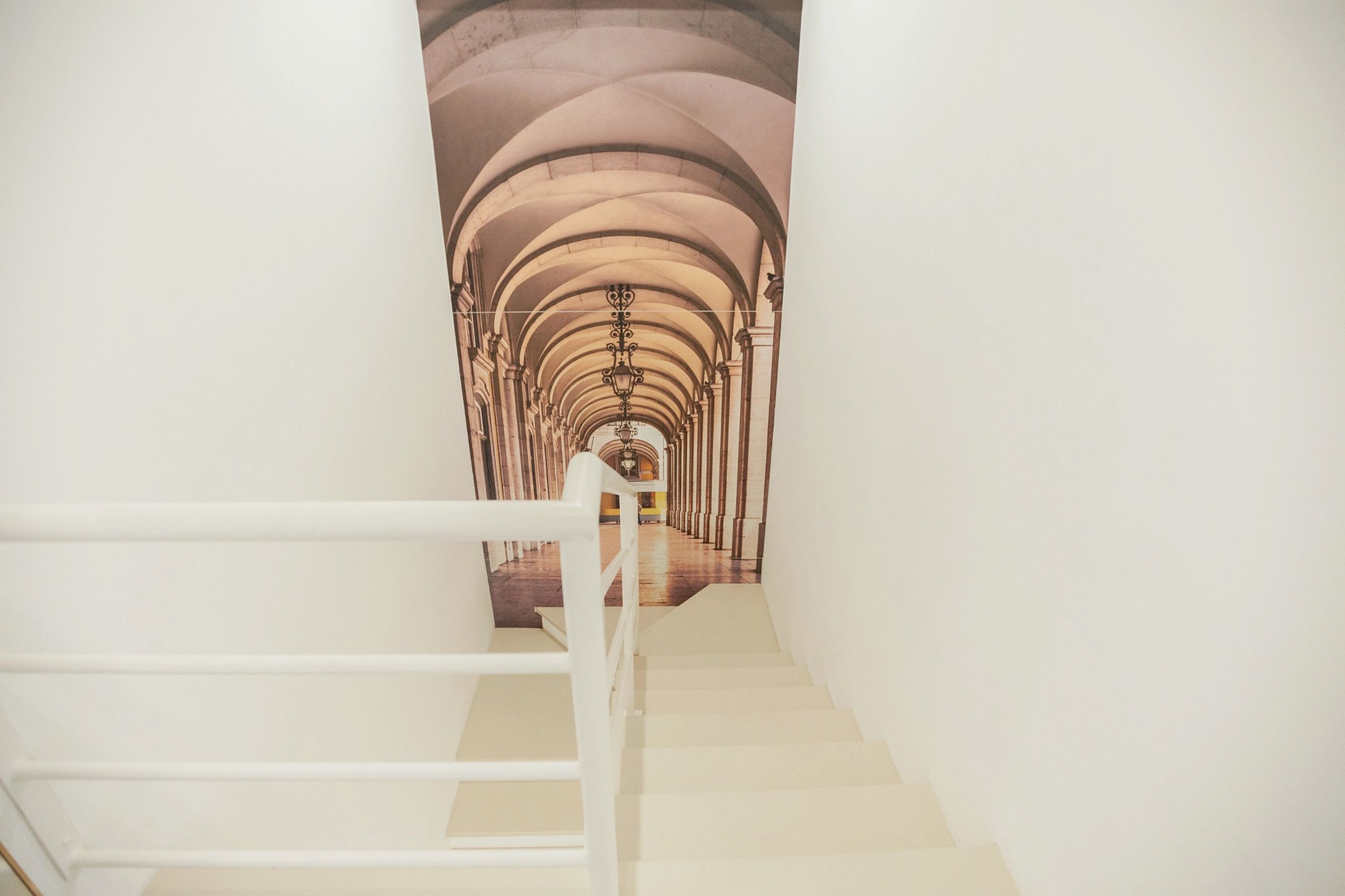 Una scala con ringhiera bianca che conduce a un soffitto ad arco.