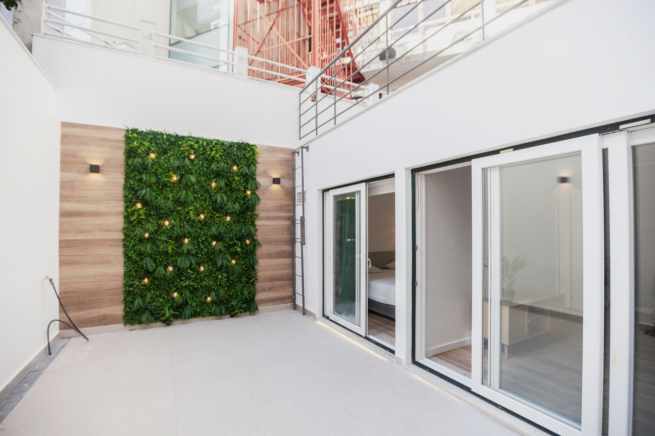 Un intérieur moderne avec un mur vert, un escalier et une porte en verre donnant sur une pièce.