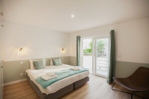 A bedroom with a bed, a chair, and a window with curtains. - FLH Salitre Modern Garden Apartment (Lisbon)