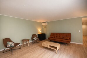 A living room with a brown sofa, two armchairs, a coffee table, and a side table with a lamp. - FLH Salitre Modern Garden Apartment (Lisbon)