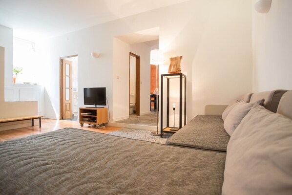 A modern living room with a sofa, a television, and a lamp.