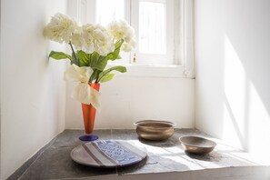A corner with a window, a vase with white flowers, and two bowls on a tiled surface.