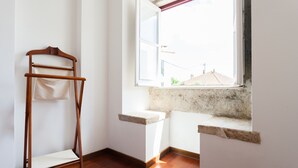 A corner room with a wooden chair, a small window, and a stone ledge. - FLH Olivais Cozy Flat (Lisbon)