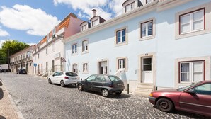 A street with cobblestone pavement, parked cars, and buildings with multiple windows and doors. - FLH Olivais Cozy Flat (Lisbon)