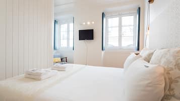 Camera d'albergo con un letto grande, una TV a schermo piatto montata a parete e una finestra con persiane blu.